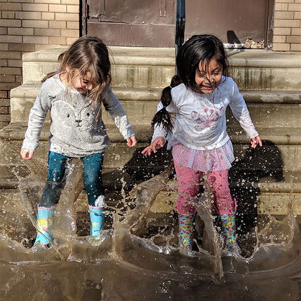 Smiling girls jumping in a puddle